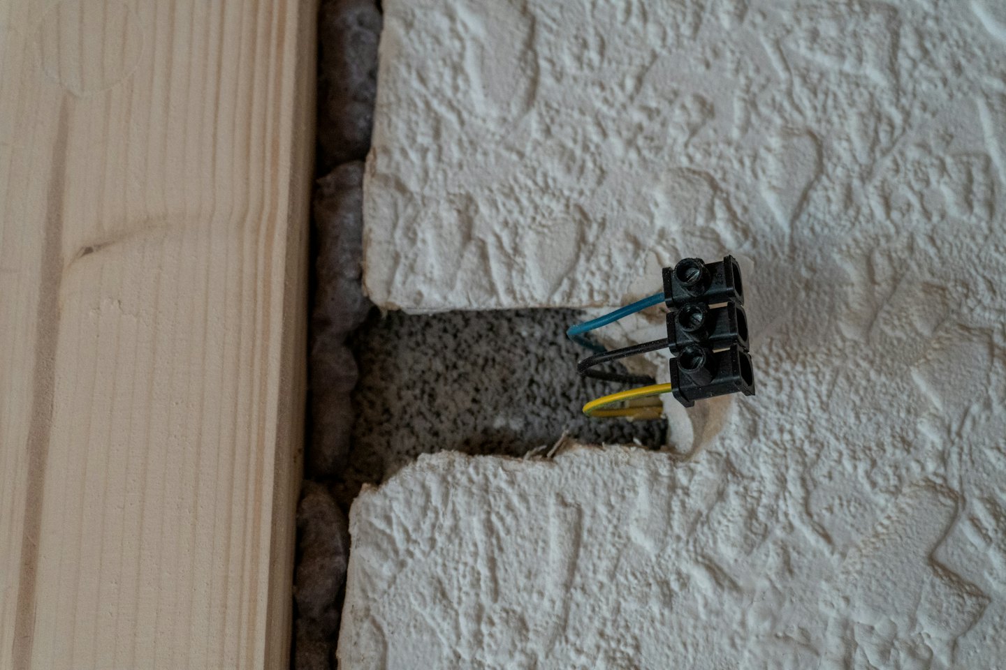 Elektrikár inštaluje modré a žlté káble do steny.